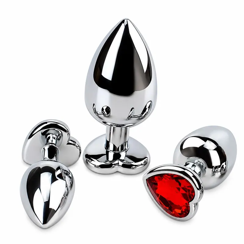 Três acessórios de metal, um com pedra em formato de coração, sobre fundo branco